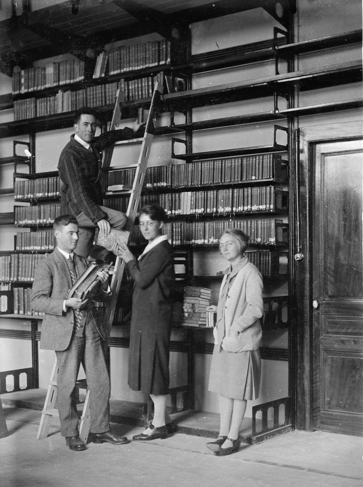 À la nouvelle bibliothèque de l'EFA, janvier 1927. De gauche à droite : Fernand Chapouthier (membre français, sur l'échelle), Paul Collart (membre suisse), Melle Yvonne Dupuy (architecte), Melle Van Leeuwen-Bomkamp (membre hollandaise, première femme membre) / EFA N447-005